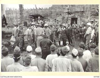 KAHILI, BOUGAINVILLE. 1945-10-01. JAPANESE TROOPS, IN FOREGROUND, WATCHING OFFICERS BEING ISSUED WITH IDENTITY DISCS PRIOR TO THEIR DEPARTURE FROM KAHILI FOR CONCENTRATION ON SAMANSO ISLAND. ..