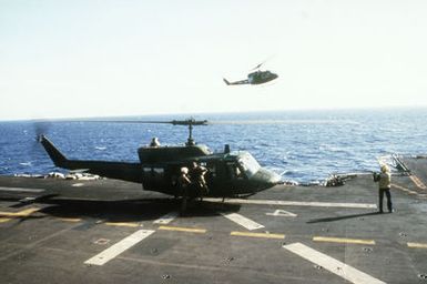 A UH-1N helicopter approaches for a landing on the flight deck of the amphibious assault ship USS GUAM (LPH-9) as another UH-1N prepares to take off. The helicopters are participating in flight operations off the coast of Beirut, Lebanon