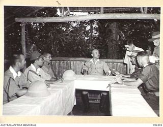 MUGUAI, MAJOR F.C. TAYLOR, BUIN LIAISON GROUP, 2 CORPS (6) THROUGH LIEUTENANT TATSU, JAPANESE INTERPRETER (5) READS INSTRUCTIONS TO MAJOR GENERAL MAGATA, JAPANESE CHIEF OF STAFF (4) DURING ..