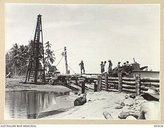ANAMO AREA, NEW GUINEA. 1944-11-24. A BULLDOZER PUSHES UP EARTHWORKS TO THE EASTERN APPROACHES OF A BRIDGE DURING CONSTRUCTION WORK BY 2/2 FIELD COMPANY, ROYAL AUSTRALIAN ENGINEERS, TROOPS CROSS AN ..