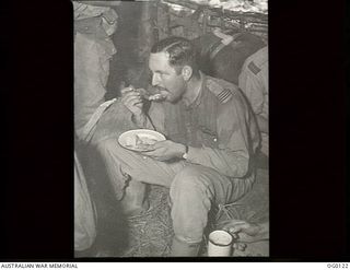 VIVIGANI, GOODENOUGH ISLAND, PAPUA. 1943-10-12. FLIGHT LIEUTENANT KEN BARBER OF WOOLOOWIN, QLD, A PILOT OF NO. 30 (BEAUFIGHTER) SQUADRON RAAF, EATS A SNACK ON RETURN TO BASE FROM AN EPIC FIGHT WITH ..