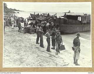 KELANOA HARBOUR, NEW GUINEA. 1944-01-13. MEMBERS OF THE 2/3RD LIGHT ANTI-AIRCRAFT REGIMENT HAULING ONE OF THEIR BOFORS 40MM ANTI AIRCRAFT GUNS ABOARD AN LCM (LANDING CRAFT MECHANISED) FOR TRANSPORT ..