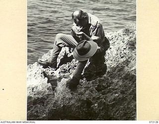 FINSCHHAFEN AREA, NEW GUINEA. 1944-04-09. NX108123 MAJOR J.H.D. EDWARDS, DEPUTY ASSISTANT DIRECTOR OF HEALTH, 2ND AUSTRALIAN CORPS, WITH THE 15TH MALARIA CONTROL UNIT EXAMINING ROCK POOLS AMONG ..