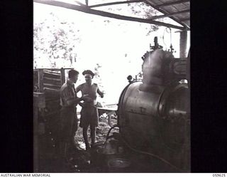DONADABU, NEW GUINEA. 1943-11-09. SX77985 SAPPER I. J. HOWARD, FACING CAMERA (1), OF THE 9TH AUSTRALIAN WORKSHOP AND PARK COMPANY, ROYAL AUSTRALIAN ENGINEERS, ENGINEER IN CHARGE OF THE STEAM ENGINE ..