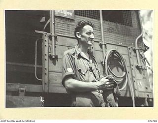 MILILAT, NEW GUINEA. 1944. NX137730 WARRANT OFFICER II, H.W. GRAINGER, IN CHARGE, 231ST AID DETACHMENT, HEADQUARTERS, 5TH DIVISION, STANDING NEAR ONE OF THE UNIT MOBILE WORKSHOPS