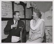 Priest, right, with Jack Benson, commentator for KGMB-TV, with Bishop National Bank of Hawaii bags in background, on May 6, 1959