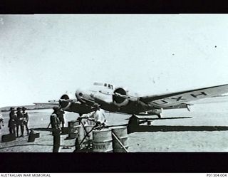 DALY WATERS, NT, 1939-10-11. FRONT VIEW OF GUINEA AIRWAYS VH-UXH, LOCKHEED 10, TWIN-ENGINE MONOPLANE "C.J. LEVIEN", BEING REFUELLED FROM 44-GALLON DRUMS. THIS AIRCRAFT CARRIED THE FIRST REGULAR ..