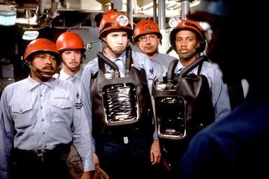 Members of a firefighting team wear protective helmets and oxygen breathing apparatuses as they prepare for a drill aboard the amphibous assault ship USS GUAM (LPH 9)