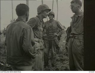 New Britain. December 1943. Private First Class (Pfc) Eugene J. Rensi, US Army, of Philadelphia, Pennsylvania, clothed only in a jacket speaks to Task Force Commander Brigadier Julian Cunningham, ..