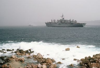 A port quarter view of the combat stores ship USS NIAGARA FALLS (AFS 3) and a large harbor tug entering Apra Harbor