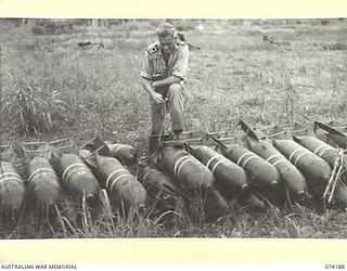 HANSA BAY, NEW GUINEA. 1944-06-21. LIEUTENANT R.G. HAYES, ROYAL AUSTRALIAN NAVY BOMB DISPOSAL UNIT, NEW GUINEA FORCE, DELOUSING A BATTERY OF 500 POUND AIRCRAFT BOMBS WHICH WERE SET AS A BOOBY TRAP ..