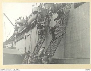 BOUGAINVILLE ISLAND, SOLOMONS. 1944-11-01. TROOPS OF THE 3RD AUSTRALIAN DIVISION AND ATTACHED TROOPS CLIMBING DOWN THE NETS OVER THE SIDE OF THE LIBERTY SHIP, LINDLEY M. GARRISON INTO AMERICAN ..