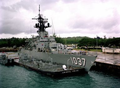 A barge (YON 293) is tied up alongside the frigate USS BRONSTEIN (FF 1037), which is moored at the US Naval Ship Repair Facility