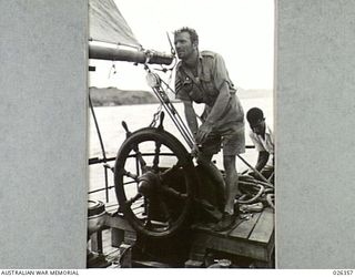 NEW GUINEA. 1942-08-04. SERGEANT BILL JOHNSON, AT THE TILLER OF HIS KETCH KEEPS A CLOSE WATCH AHEAD FOR REEFS. THIS KETCH, WAS FORMERLY IN USE AS A RUBBER BOAT