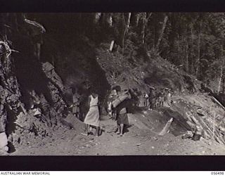 REINHOLD HIGHWAY, NEW GUINEA, 1943-08-31. NATIVES CLEANING THE BENCH ON THE ROAD AT THE 26 MILE POINT