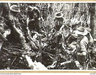 SHAGGY RIDGE, NEW GUINEA. 1943-12-27. TROOPS OF THE 2/16TH AUSTRALIAN INFANTRY BATTALION, 21ST AUSTRALIAN INFANTRY BRIGADE UNEARTH A DEAD JAPANESE SOLDIER ON THE "PIMPLE" AFTER THE BATTLE. ..