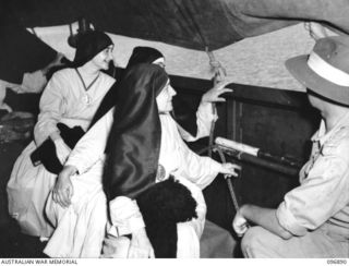 Vunapope, New Britain. A group of sisters looking through the canopy of the Army barge which is taking them out to the motor launch Gloria. They are being evacuated from the Mission in Ramale ..