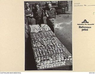 WEWAK AREA, NEW GUINEA, 1945-06-13. WO 2 W. TAYLOR (1) AND WO 2 J. BUCKERIDGE (2), INSTRUCTORS, LHQ COOKING AND CATERING SCHOOLS, INSPECTING AN ARRAY OF BAKED FOOD. THEY GIVE ADVICE TO COOKS FROM ..