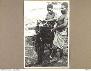 DUMPU, NEW GUINEA. 1943-12-06. NATIVES EMPLOYED BY THE 18TH AUSTRALIAN ANTI-MALARIAL CONTROL UNIT FILLING THEIR KNAPSACK SPRAYS WITH MOSQUITO KILLING SPRAY