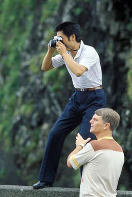 A member of the Chinese People's Liberation Army Air Force Song and Dance Troupe takes a photograph at Pali Lookout during a tour of the island. The troupe is here on the final stop of its US tour