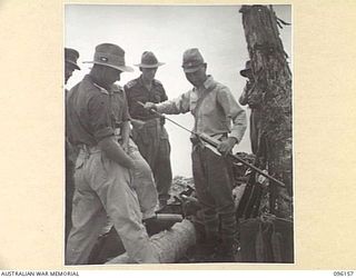 MUSCHU ISLAND, NEW GUINEA. 1945-09-10. JAPANESE OFFICER EXPLAINING TO THE UNITED STATES ARMY INTERPRETER AND MEDICAL OFFICERS OF 6 DIVISION, THAT HIS SWORD IS THE PRIZE ONE ON MUSCHU ISLAND. THE ..