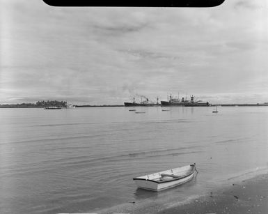 Beach scene, including row boats on water and fishing vessels at wharf, Lautoka, Fiji