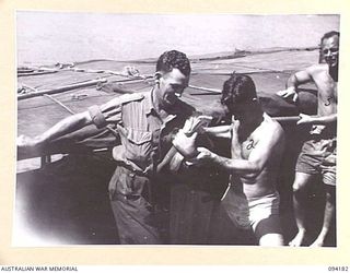 BOIKEN, NEW GUINEA. 1945-07-15. SICK MEMBERS OF 2/7 CAVALRY (COMMANDO) REGIMENT BEING TRANSFERRED TO A MOTOR LAUNCH WHICH WILL TAKE THEM TO CAPE WOM