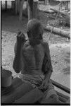 Elderly man sits on shady veranda