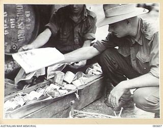 BABIANG, NEW GUINEA. 1944-11-20. A 2/10 COMMANDO SQUADRON QUARTERMASTER SERGEANT AND HIS ASSISTANT, OPEN THE AIR- DROPPED SUPPLIES AND EXAMINE THE INTACT CONTENTS