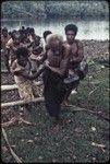 Canoe-building: men pull roughly shaped canoe hull onto the beach at Tukwaukwa village