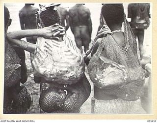 KIARIVU, NEW GUINEA, 1945-08-17. REFUGEE NATIVES LINED UP ON THE AIRSTRIP FOR COUNTING AND INSPECTION BY CAPTAIN R.R. COLE, THE ASSISTANT DISTRICT OFFICER, AUSTRALIAN NEW GUINEA ADMINISTRATIVE ..