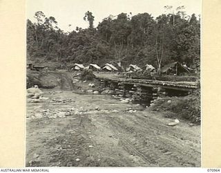 ZENAG, NEW GUINEA, 1944-02-28. THE 120 FOOT SPAN CRIB PIER BRIDGE OVER TIMNE WATERS. TAKEN 57 MILES FROM WAU, THE FORD TO THE LEFT OF THE BRIDGE LEADS TO THE CAMP OF NO.4 PLATOON, 2/1ST MECHANICAL ..