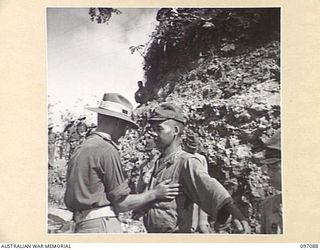 MOUNT SHIBURANGU, WEWAK AREA, NEW GUINEA. 1945-09-21. LIEUTENANT K.F.D. DOWE, HEADQUARTERS 6 DIVISION, SEARCHING A JAPANESE SOLDIER OF 18 JAPANESE ARMY FOR WEAPONS OR SHARP INSTRUMENTS AT A ..