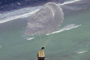 A package containing Christmas presents falls with its parachute onto a local island. The donated gifts were collected by volunteers from the 43rd Security Police Squadron, the 605th Military Airlift Support Squadron, and the 43rd Munitions Maintenance Squadron