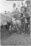 Pig festival, sacred stone house: decorated men enter house where fertility stones have been hung, boys with drums outside