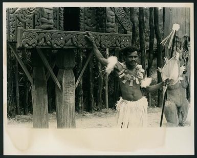 [Man posing in front of a pātaka]