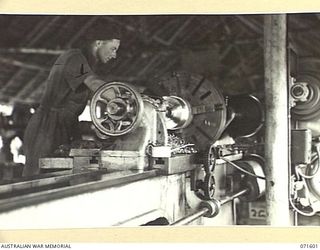 LABU POINT, LAE, NEW GUINEA, 1944-03-24. VX91868 CRAFTSMAN S. B. PEARCE, TURNING A COUPLING FOR A PROPELLER SHAFT ON A 36 INCH LATHE IN THE MACHINE SHOP AT THE 1ST WATERCRAFT WORKSHOP