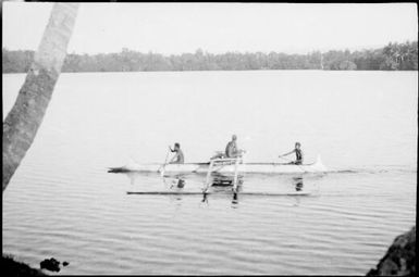 Three people in an outrigger canoe with two of them paddling, New Guinea, ca. 1929 / Sarah Chinnery