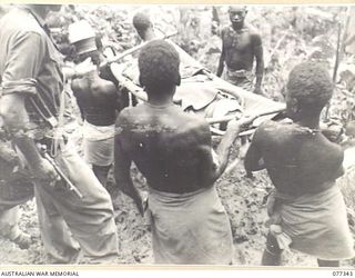 TOROKINA AREA, BOUGAINVILLE ISLAND. 1944-11-30. A JAPANESE PRISONER, WOUNDED DURING THE ENEMY COUNTER-ATTACK ON LITTLE GEORGE HILL, BEING CARRIED DOWN GEORGE HILL TO THE ADVANCED DRESSING STATION ..