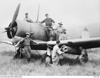 GUSAP, RAMU VALLEY, NEW GUINEA. 1944-01-02. 405747 FLYING OFFICER R.D. LEE-WARNER (5) WITH MEMBERS OF NO. 4 (TACTICAL RECONNAISSANCE) SQUADRON'S GROUND STAFF WHO ARE ENGAGED IN ATTACHING CONTAINERS ..