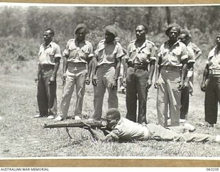 SOUTHPORT, QLD. 1944-01-18. A NEW GUINEA POLICE BOY FIRING A .303 RIFLE AT A TANK OF THE 4TH ARMOURED BRIGADE DURING A DEMONSTRATION OF STRENGTH OF THE ARMOUR PLATING