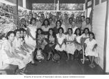 Members of the resurvey party posing with women who served food and provided music at a dinner party, Likiep Island, summer 1949