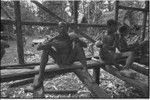 House-building: men share meal of yams, in building under construction