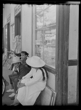 Street scene with people resting on bench next to store, Papeete, Tahiti