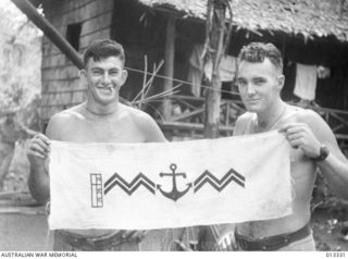 1942-10-01. NEW GUINEA. MILNE BAY. AUSTRALIAN SOLDIERS HOLDING A JAPANESE EMBLEM CAPTURED DURING THE MILNE BAY FIGHTING