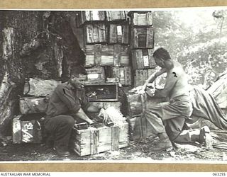 HUON GULF, NEW GUINEA. 1944-01-01. WX10831 LANCE CORPORAL G. A. CRIDDLE (1) AND WX5921 PRIVATE R. A. HARTNETT O F THE 9TH DIVISION SALVAGE UNIT EXAMINING MEDICAL STORES ABANDONED BY THE JAPANESE ..