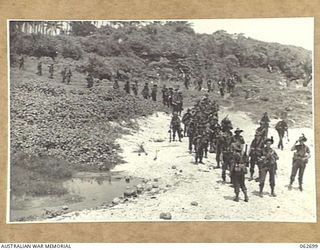 KANOMI BEACH, NEW GUINEA. 1944-01-05. TROOPS OF THE 2/23RD AUSTRALIAN INFANTRY BATTALION 26TH AUSTRALIAN INFANTRY BRIGADE, 9TH AUSTRALIAN DIVISION WAITING TO BOARD BARGES FOR THEIR TRIP UP THE ..