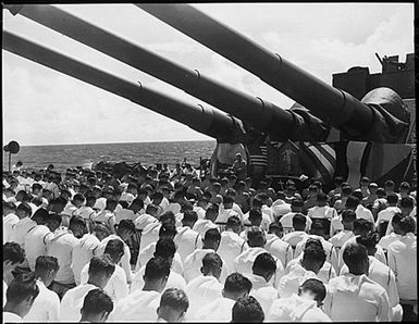 The crew of the USS SOUTH DAKOTA stands with bowed heads, while Chaplain N. D. Lindner reads the benediction held in honor of fellow shipmates killed in the air action off Guam on June 19, 1944.