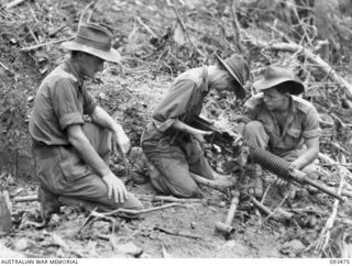 WEWAK AREA, NEW GUINEA. 1945-06-28. TROOPS OF 2/8 INFANTRY BATTALION CLEANING A CAPTURED JAPANESE TYPE 92 MACHINE GUN BEFORE TESTING IT. CAPTURED AMMUNITION IS AVAILABLE AND THE MEN INTEND USING IT ..