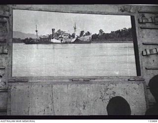 LAE, NEW GUINEA. 1943-10-01. LOOKING THROUGH AN OPENING OF A LANDING CRAFT VEHICLE, THE MALAHANG CAN BE SEEN WRECKED ON THE BEACH